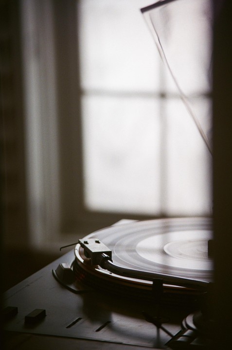 A record player with a spinning record is visible in the foreground, with a window in the background.