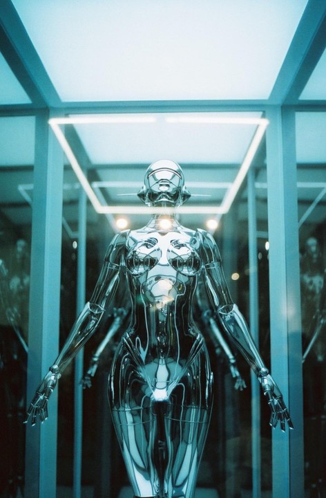 A chrome mannequin stands in a display case with neon lighting.