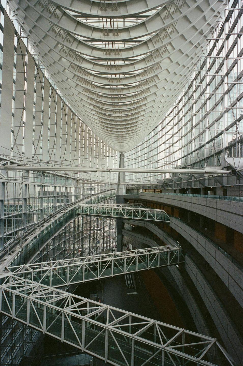 A large, modern building interior features multiple levels of walkways and a high, arched ceiling.