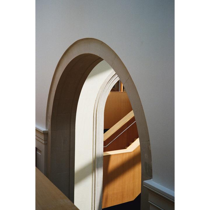 Sunlight casts shadows through a series of arches and staircases in a gallery.