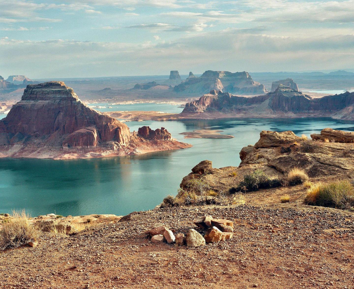 A wide shot shows a lake surrounded by rock formations under a cloudy sky.