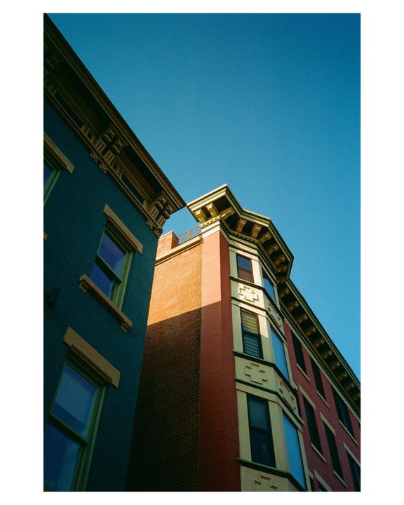 Two colorful buildings with ornate cornices are visible against a clear blue sky.