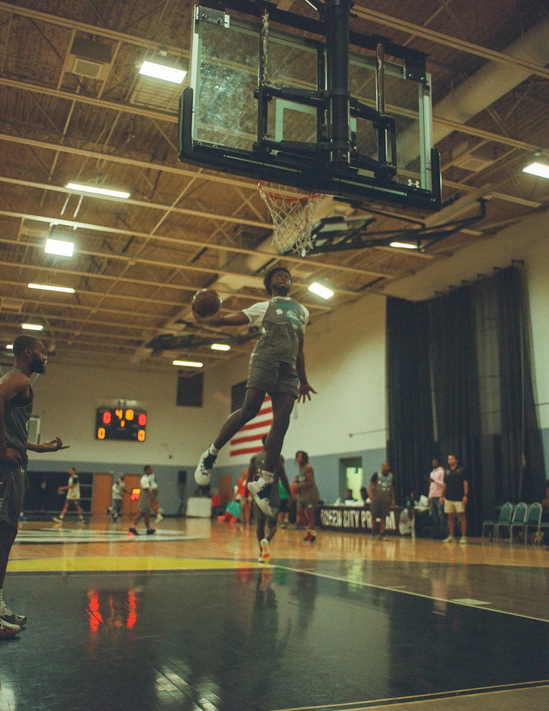 A man in mid-air holds a basketball near a hoop on an indoor court.
