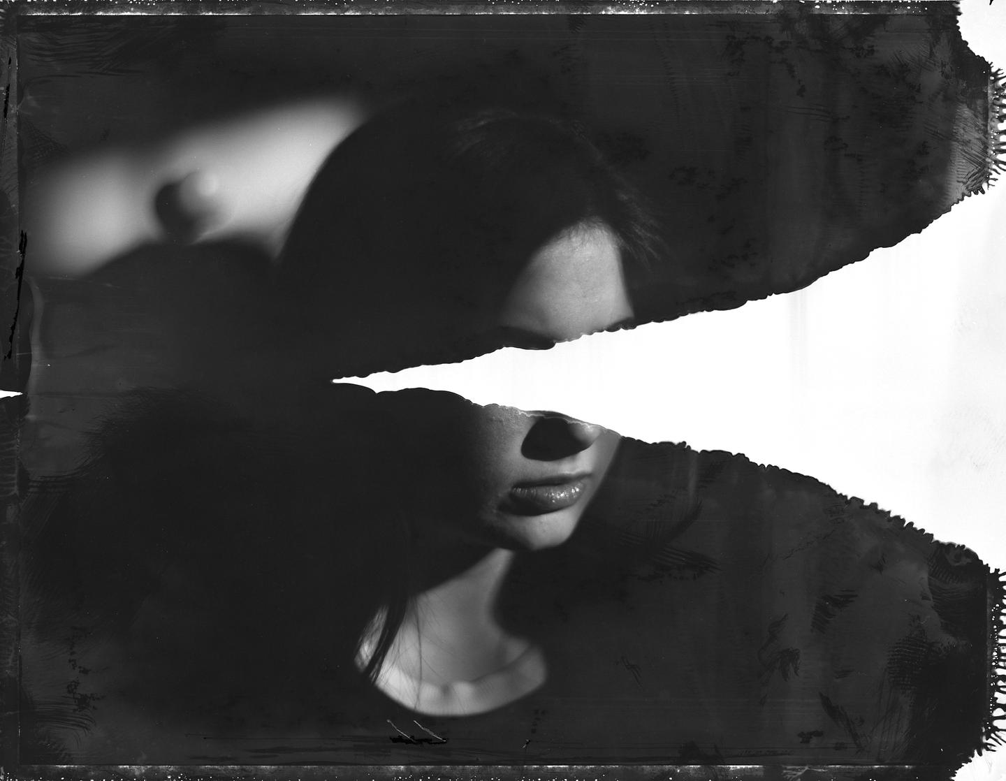 A woman's face is partially obscured by a large white horizontal stripe across her eyes in a black and white portrait.