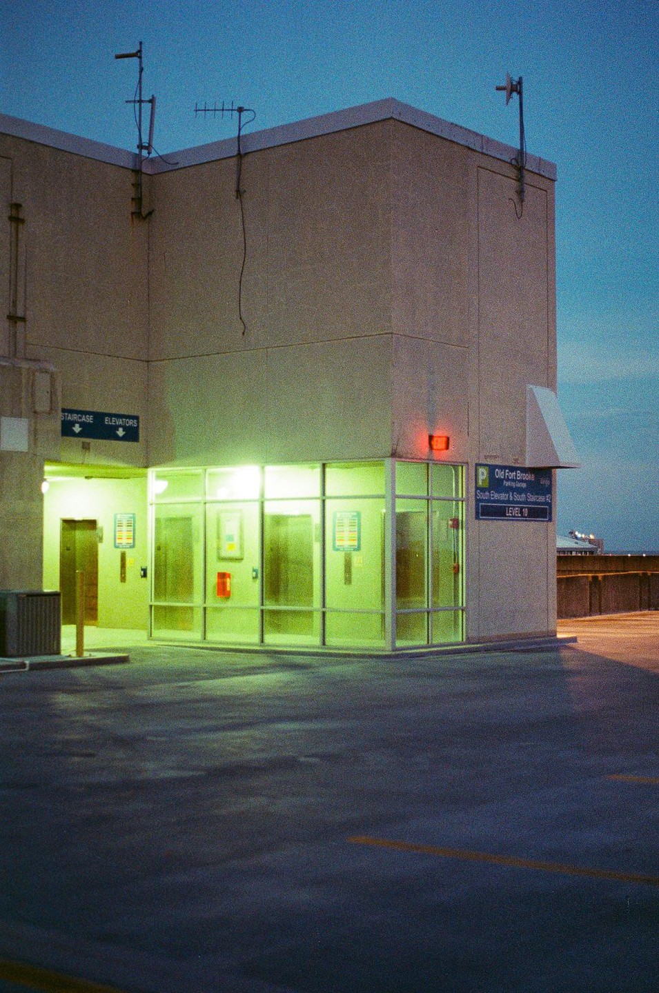 A building with bright green lights illuminating its entrance stands against a dark blue sky.