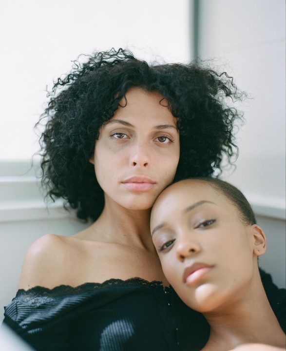 Two women are posing for a portrait, one resting her head on the other's shoulder.
