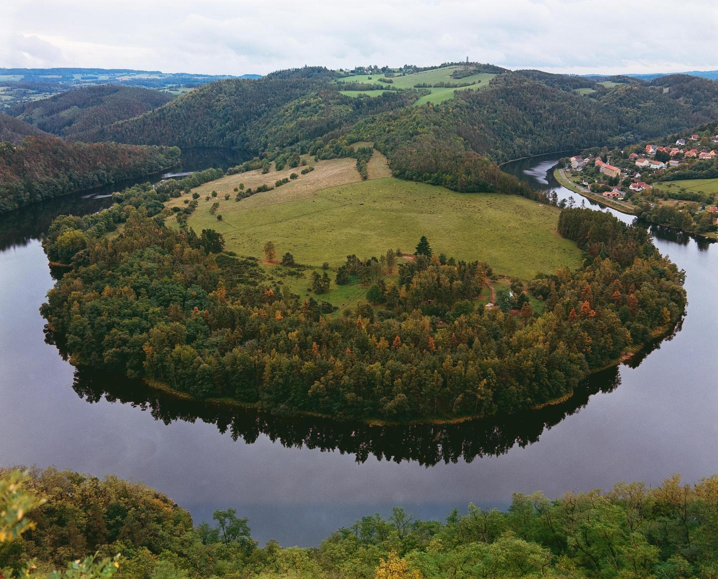 A river meanders through a valley with a small town visible on the right bank.