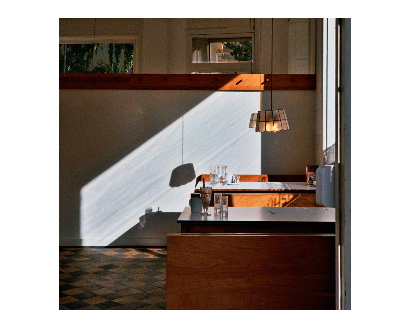Sunlight streams into a diner booth with empty glasses on the table.