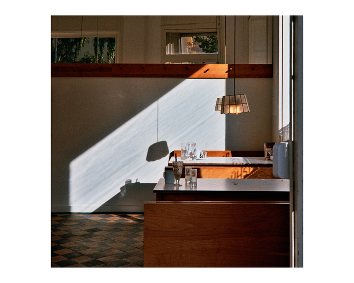 Sunlight streams into a diner booth with empty glasses on the table.