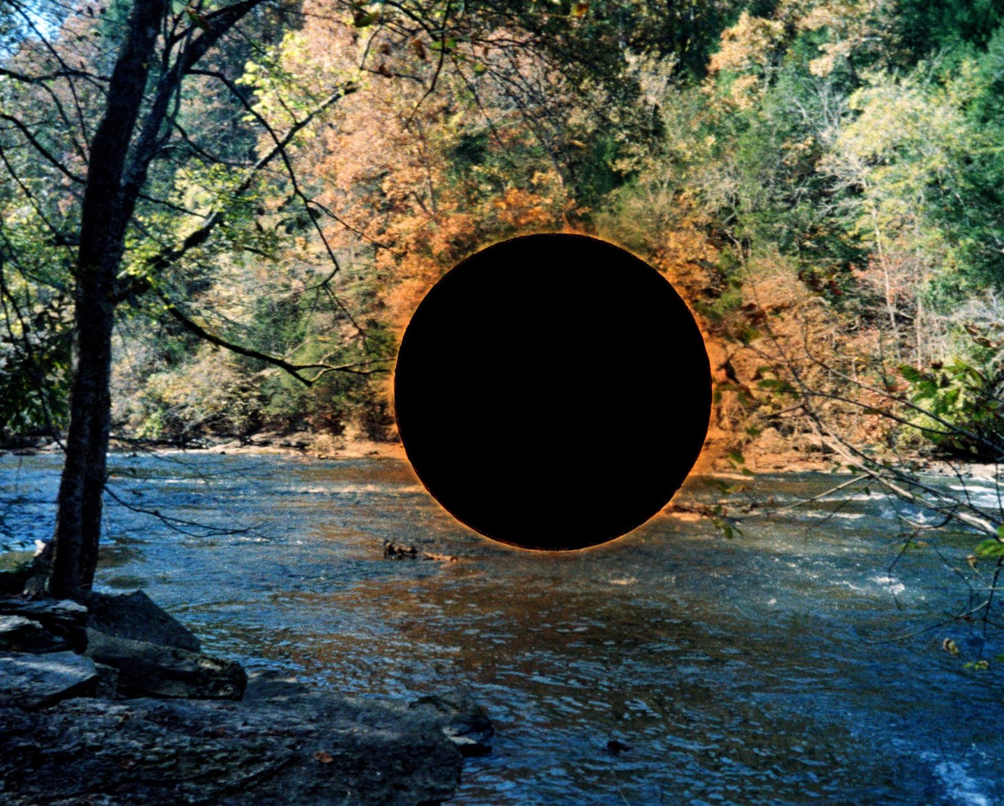 A black circle with an orange glow floats above a river surrounded by autumn trees.