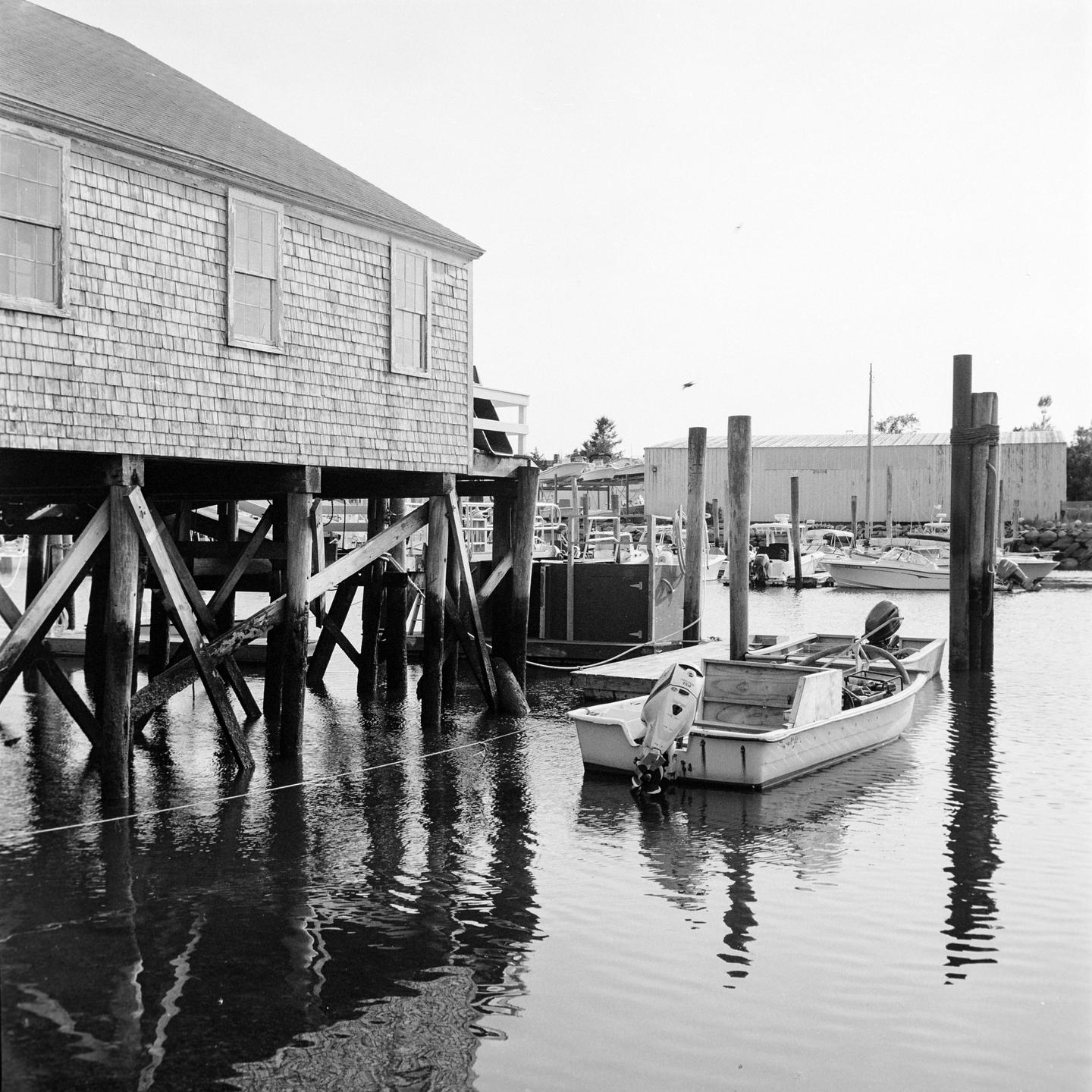 A small boat is moored next to a wooden building on stilts over the water.