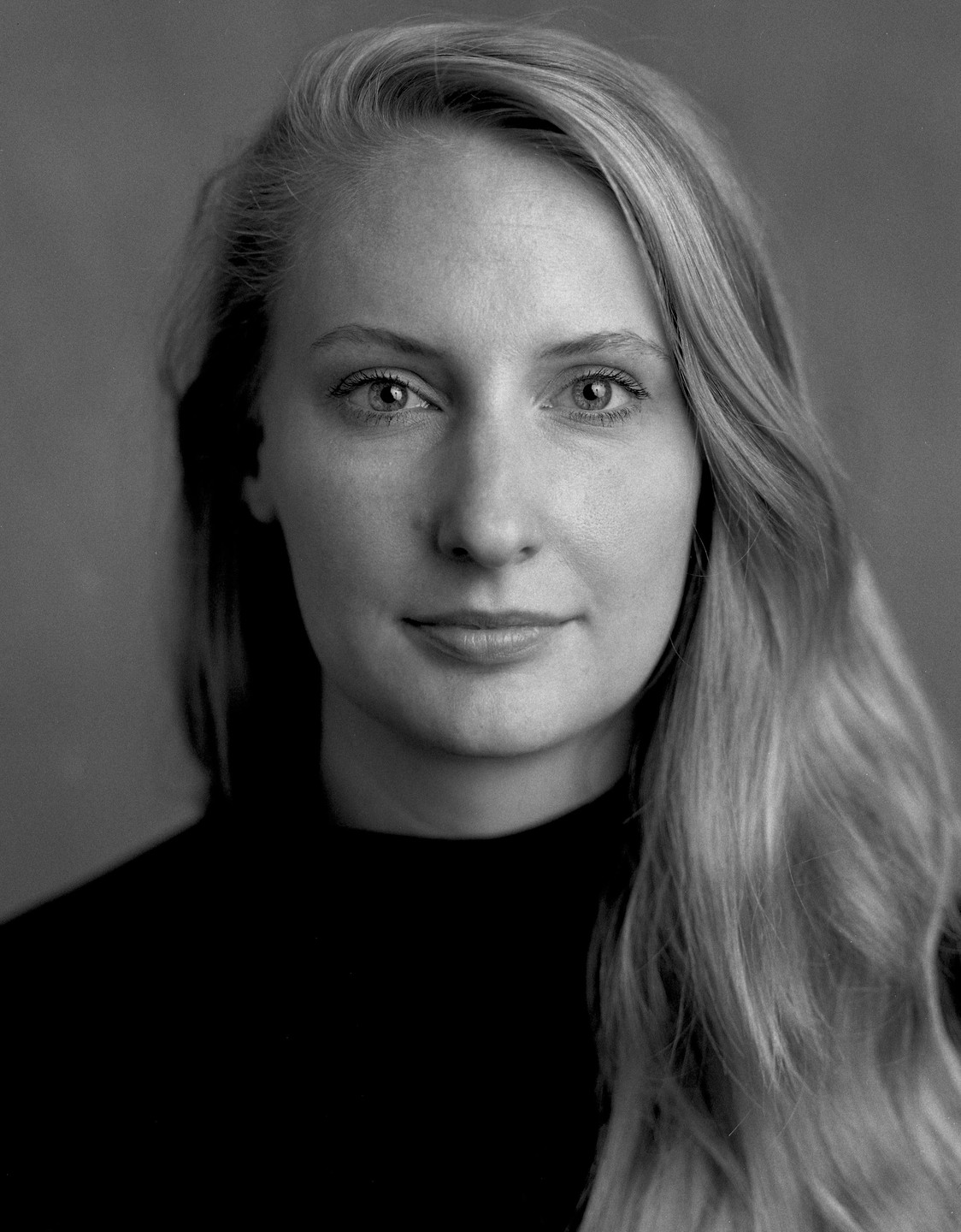 A woman with long hair looks directly at the viewer.