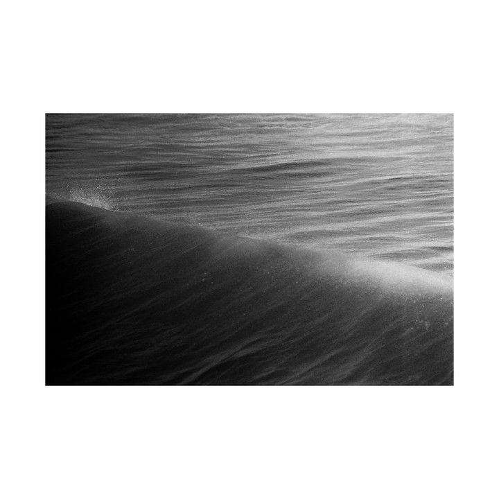 A black and white close-up shows a wave cresting with spray.