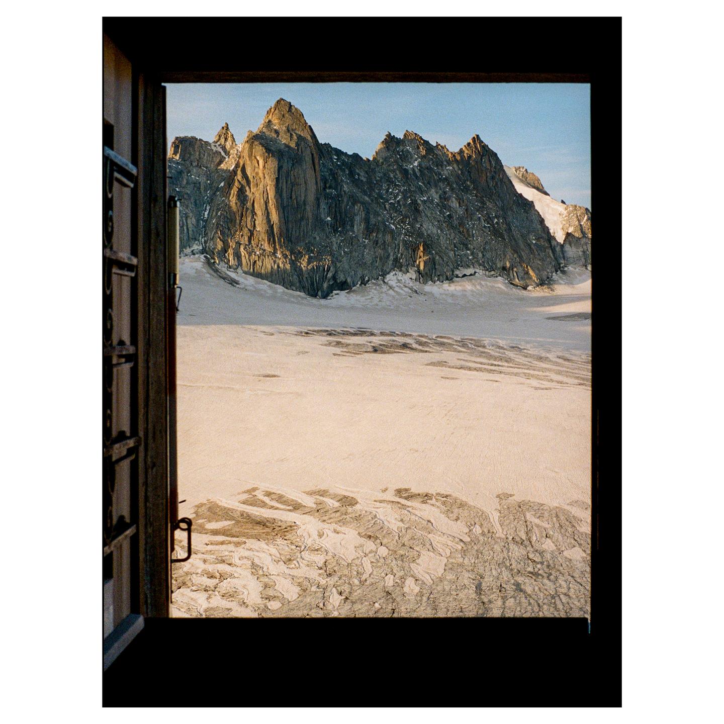 A glacier and mountain range are visible through an open window.
