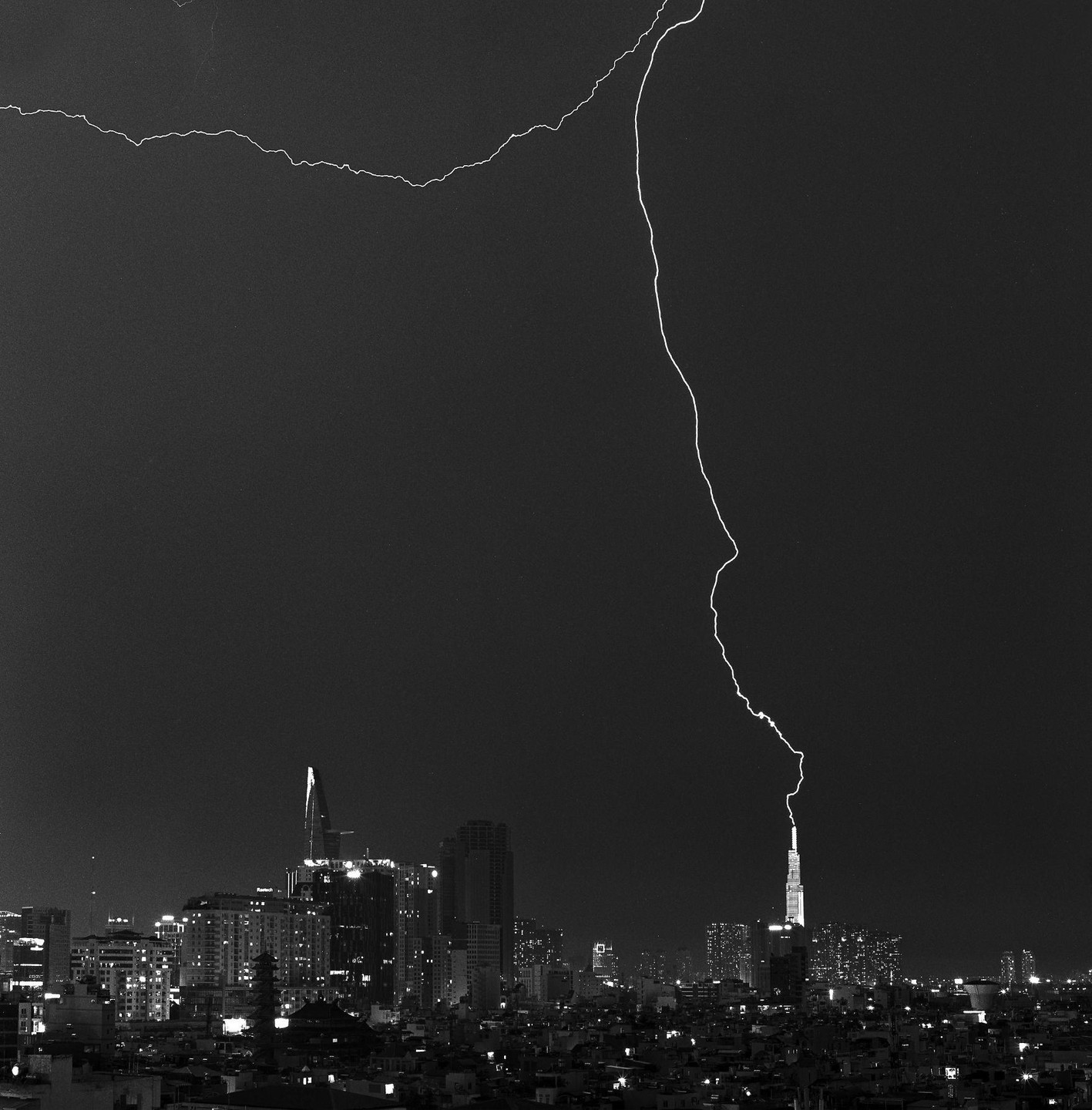 A bolt of lightning strikes a tall building in a city at night.