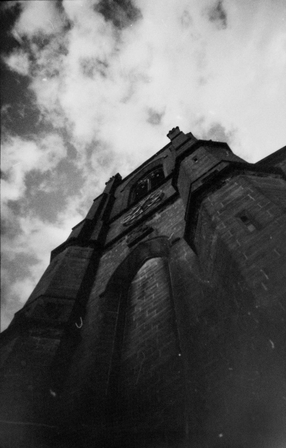 A low-angle view shows a church tower with a clock against a cloudy sky.