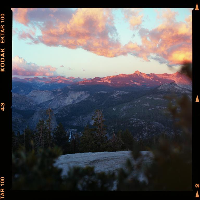 A mountain landscape is visible under a sky with pink clouds at sunset.