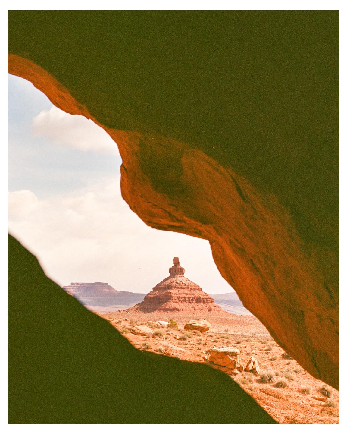 A red rock formation is framed by two dark rock formations in the foreground.