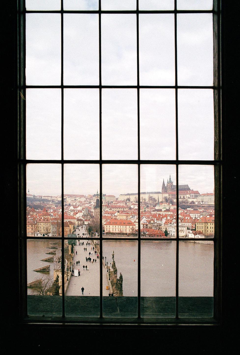 A view of a city with a river and a bridge, seen through a window with a grid.