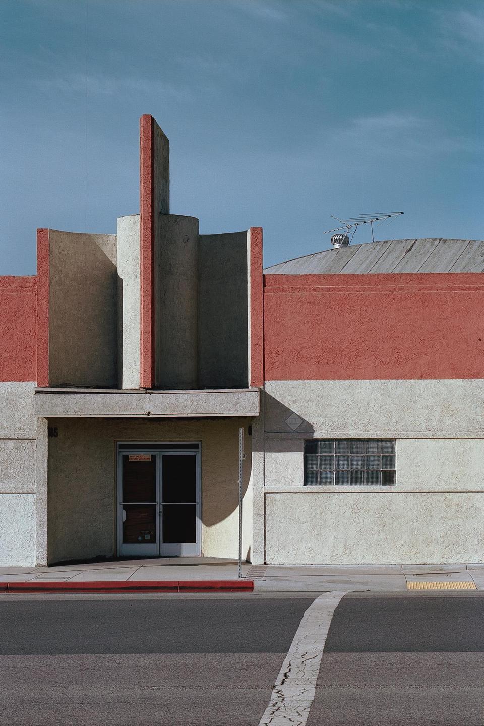A building with red and beige walls features an art deco facade and a glass block window.
