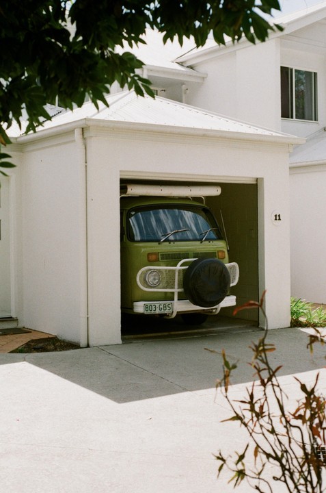 A green camper van is parked inside a white garage with the number 11 on the wall.