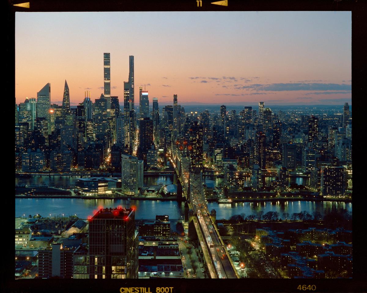 A city skyline with a bridge over a river is visible at dusk.