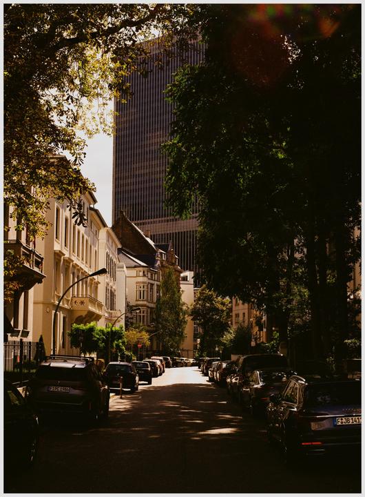 A street with parked cars and buildings is visible, with a tall skyscraper in the background.