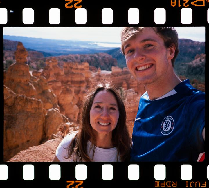 A man and a woman smile at the camera with a desert landscape in the background.