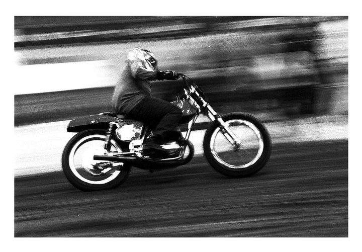 A person on a motorcycle speeds across a blurred background.