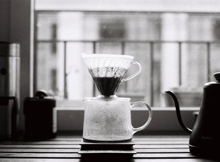 A coffee pour-over setup sits on a counter in front of a window.