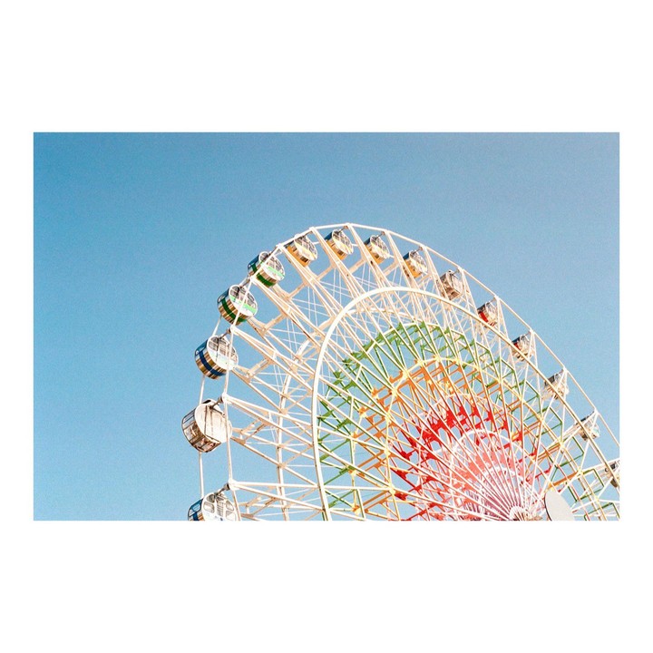 A colorful ferris wheel stands against a clear blue sky.