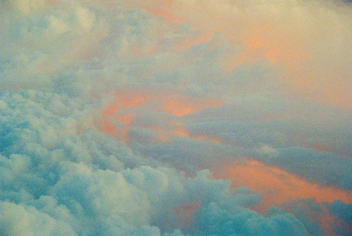 Clouds are visible from above with a sunset glow.