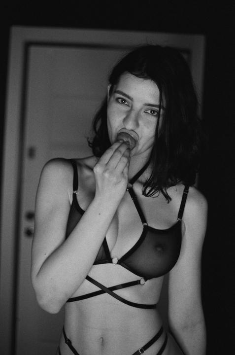 A woman in lingerie holds a finger to her mouth.