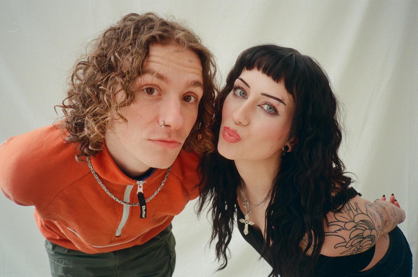 A man and a woman pose for a close-up portrait with a white background.