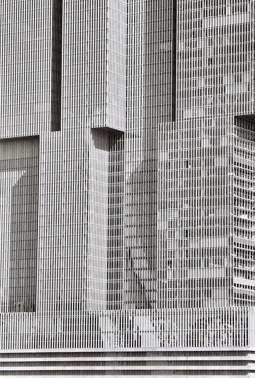 A tall building with many vertical lines and a few horizontal elements is shown in a black and white architectural photograph.