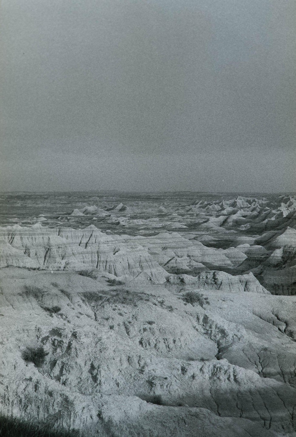 A vast landscape of eroded hills and valleys stretches under a cloudy sky.