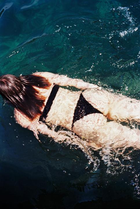 A woman with long hair swims in a pool, viewed from above.