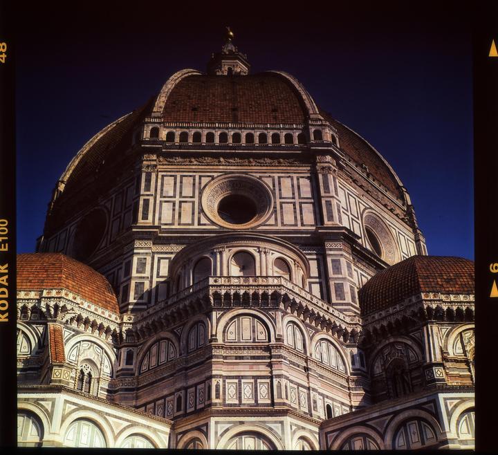 A low-angle view shows the intricate details of a large domed cathedral against a deep blue sky.