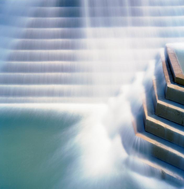 A long exposure captures the smooth flow of water over a series of steps in a fountain.