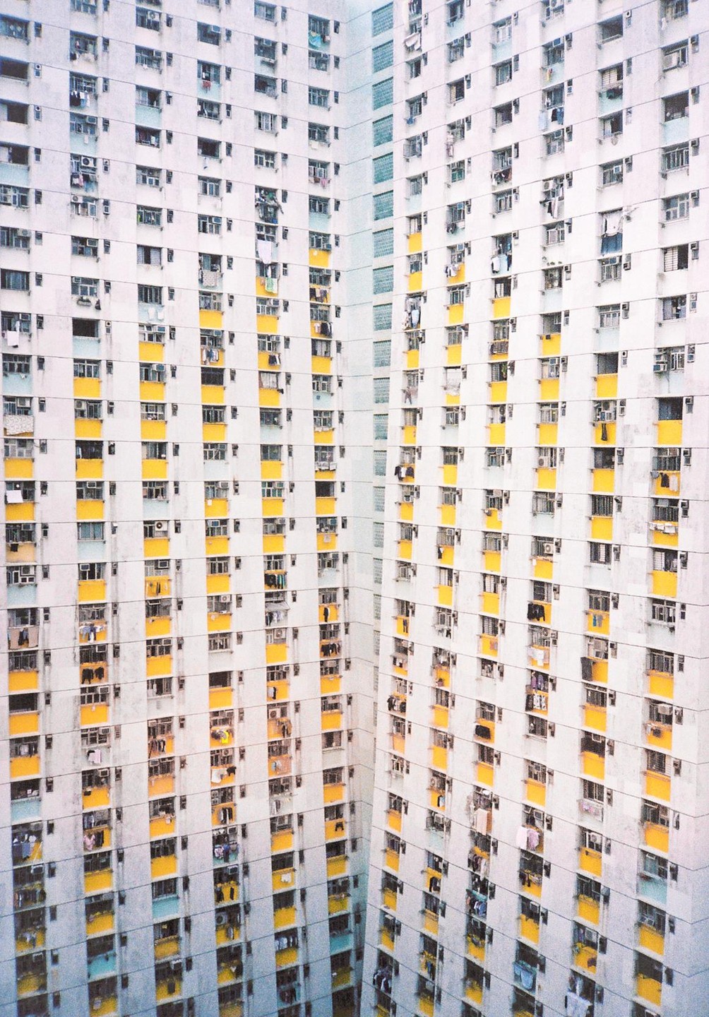 A tall residential building with many windows and balconies is shown from an elevated perspective.