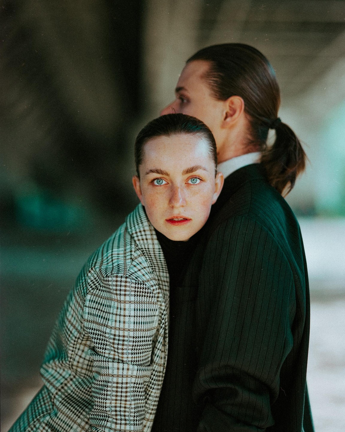 A woman with blue eyes looks at the viewer while leaning against a man.