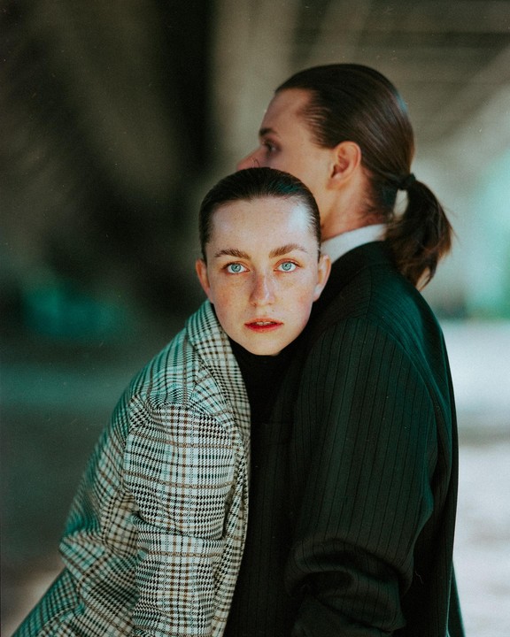 A woman with blue eyes looks at the viewer while leaning against a man.