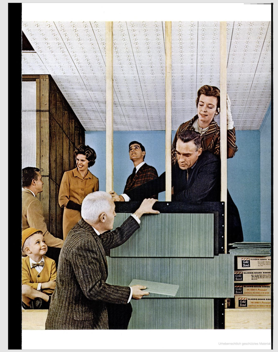 A group of adults and a child are gathered around a man installing siding panels on a wall.