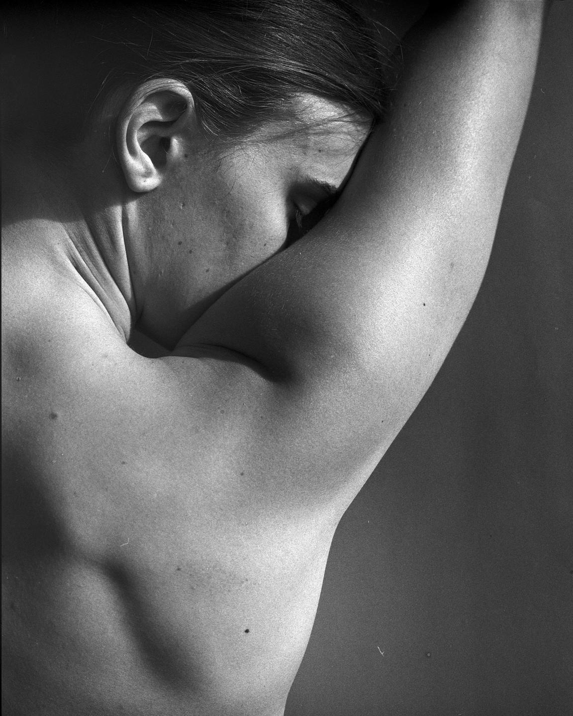 A woman's back and arm are visible as she rests her head on her arm.