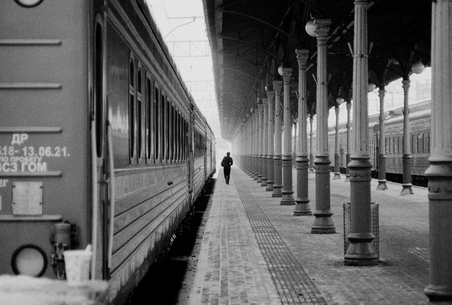 A man walks along a train platform next to a train.