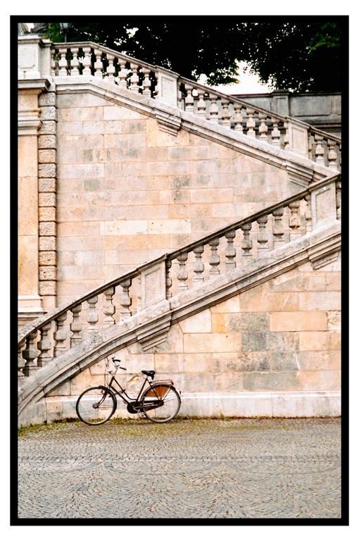 A bicycle is parked at the base of a grand stone staircase with a balustrade.