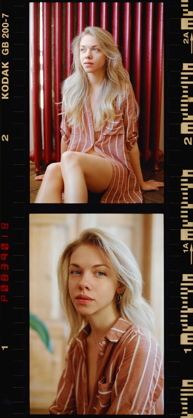 A woman with long blonde hair sits on the floor in a striped shirt, with a red radiator behind her.