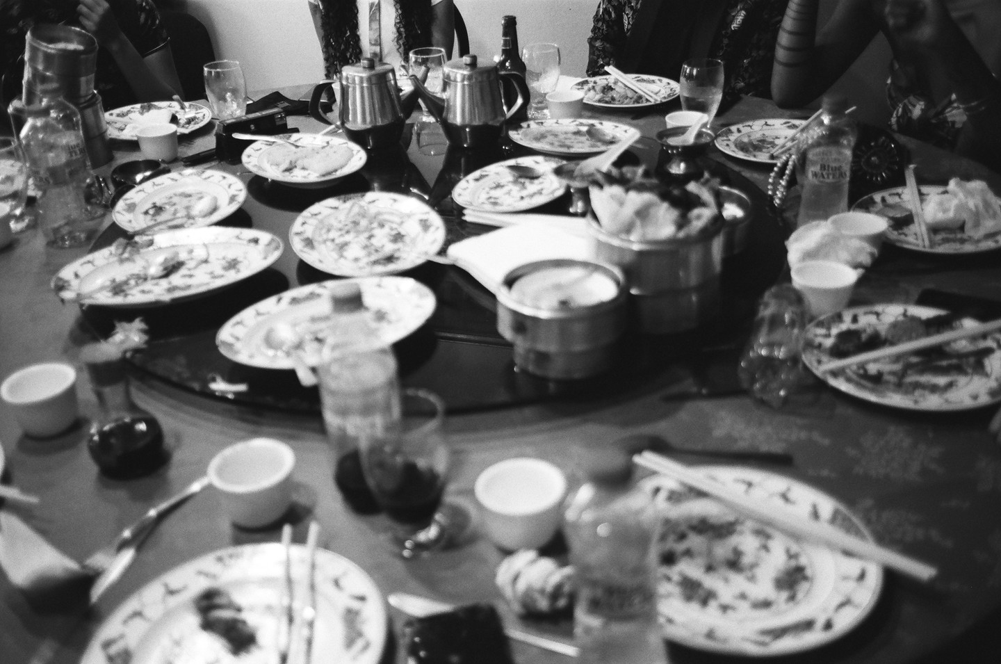 A table is covered with many dirty plates, cups, and bottles after a meal.