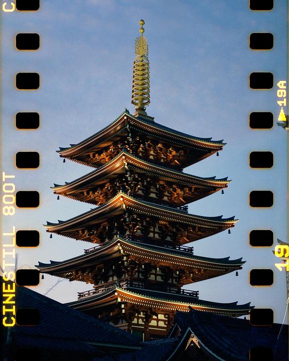 A five-storied pagoda with a golden spire stands against a clear sky.
