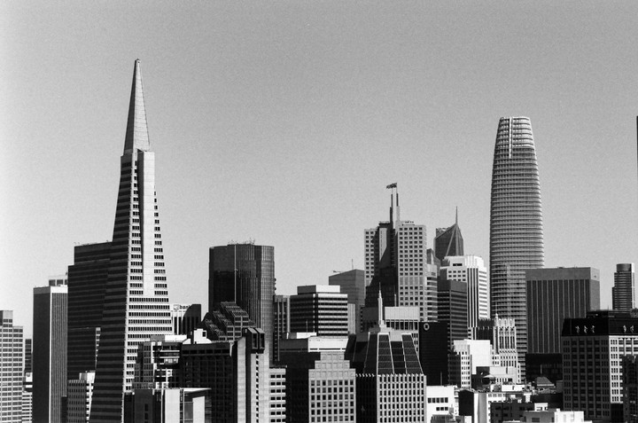 A black and white cityscape shows numerous skyscrapers under a clear sky.